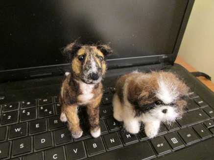 A needle felted brindle dog and Shih Tzu sitting on a computer