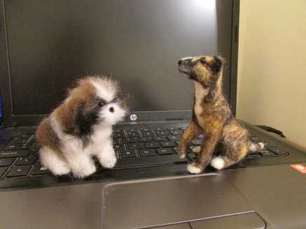 Side view of a needle felted brindle dog and Shih Tzu sitting on a computer