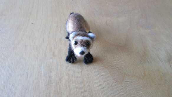 A needle felted brown ferret standing on a table