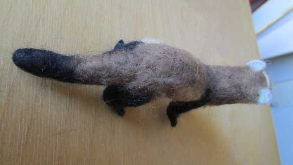 back view of a needle felted brown ferret standing on a table